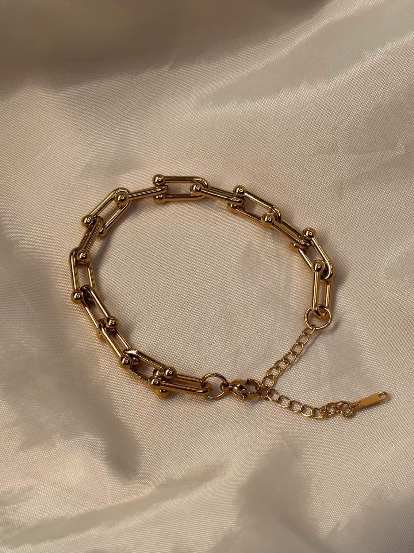 The Chunky Bracelet on cream silk showing its bold U-shaped gold links
