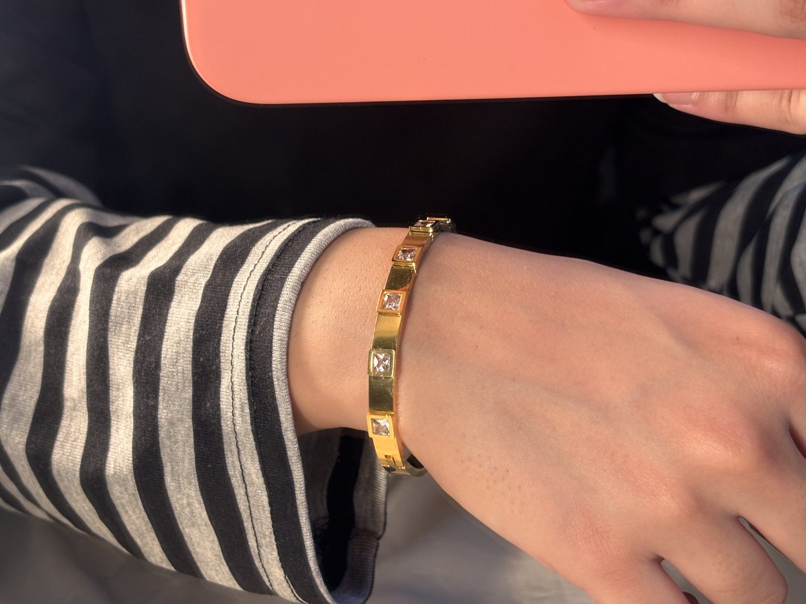The Cinderella Bracelet worn on the wrist with a striped sleeve